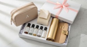An elegant travel gift set featuring a monogrammed toiletry bag, mini skincare bottles, gold jewelry roll, and cashmere socks neatly arranged inside a white gift box with ribbon